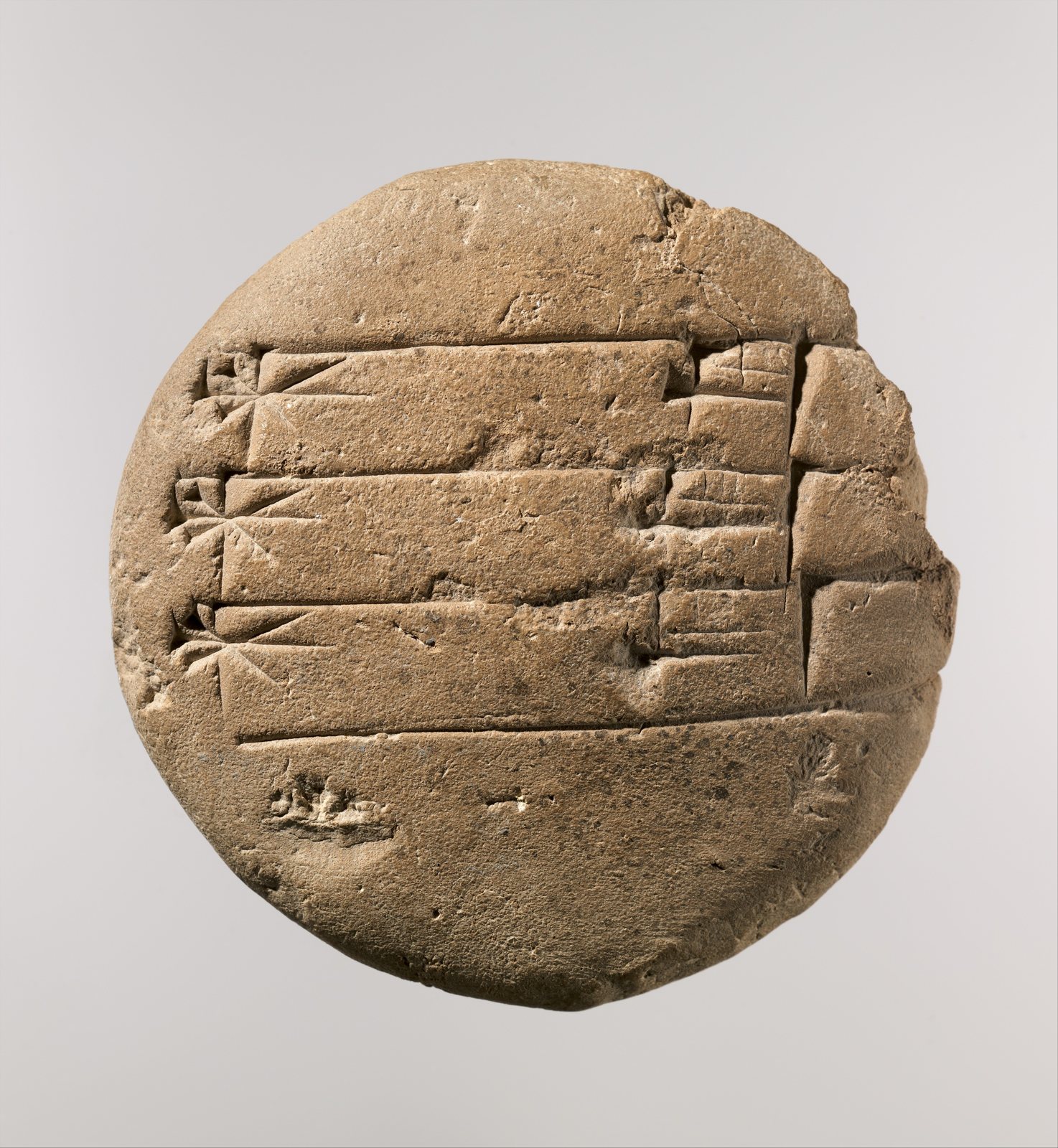 Photo of a round clay school exercise tablet with rows of cuneiform signs, Mesopotamia, c. 20th to 16th century BC