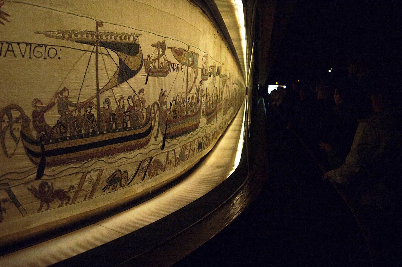 The Bayeux Tapestry in its former display case in Bayeux, 2015. Photo: Supercarwaar, CC BY-SA 4.0, via Wikimedia Commons