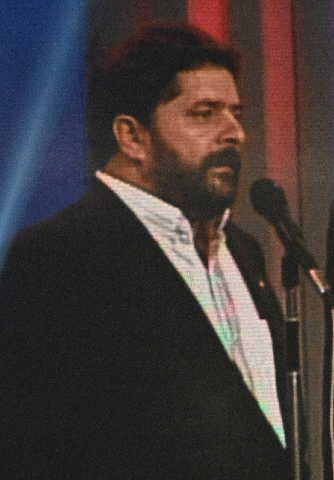 Photograph of Luiz Inácio Lula da Silva, bearded and in a dark jacket, speaking at a microphone during the 1989 campaign