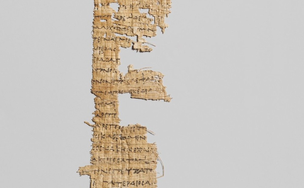 Close-up photograph of a torn strip of ancient papyrus with lines of Greek handwriting, a third-century BC fragment of Homer's Odyssey