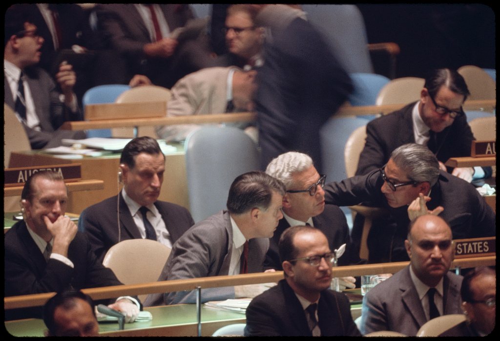 Colour photograph of delegates seated at the United States and Austria desks in the United Nations General Assembly hall, New York, late 1960s