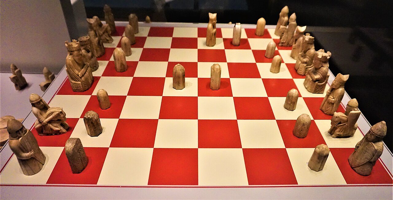 Photograph of the twelfth-century Lewis chessmen, carved from walrus ivory, set out on a red and white board in the British Museum